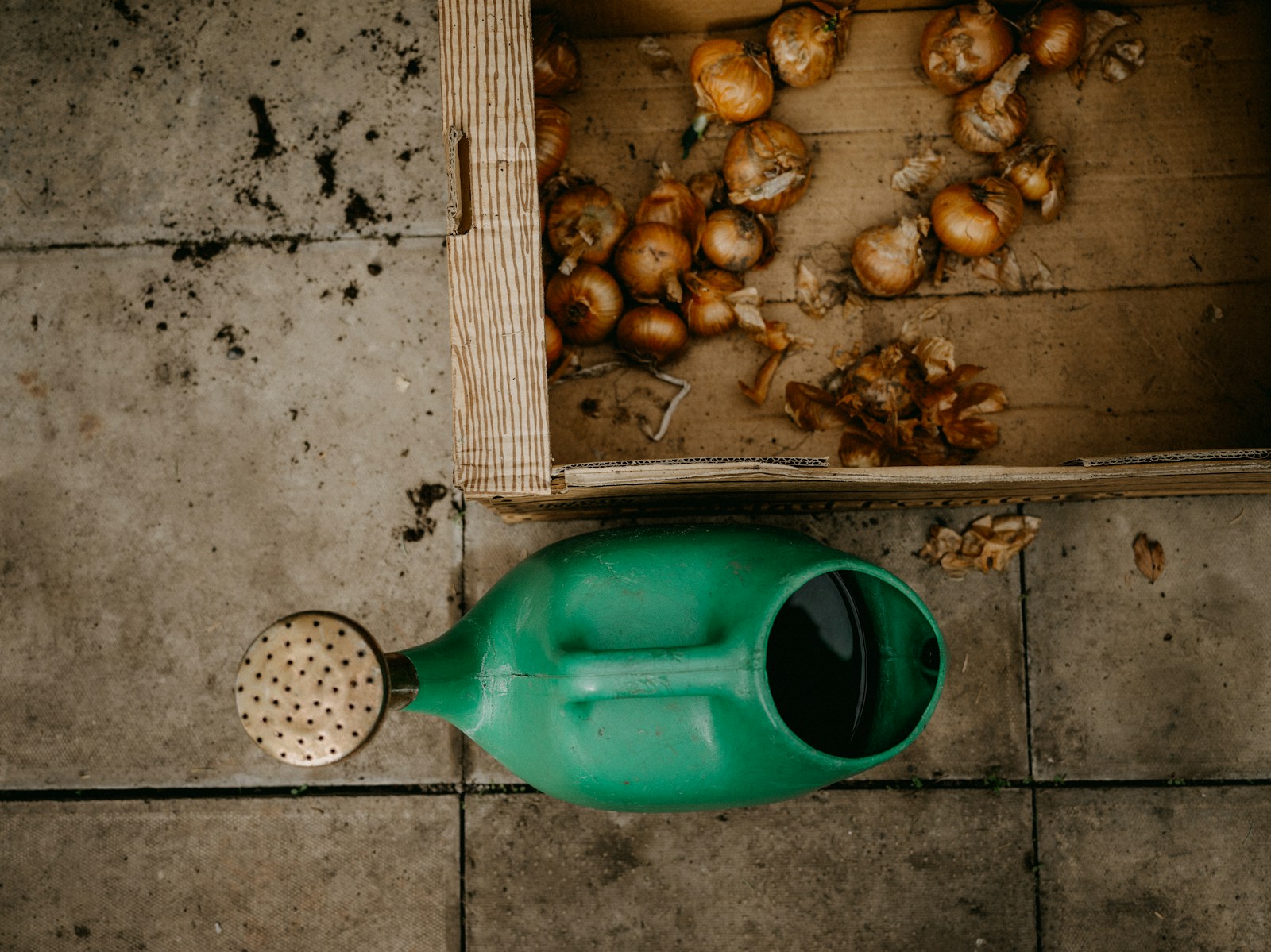 a green watering can sitting on top of a tile floor