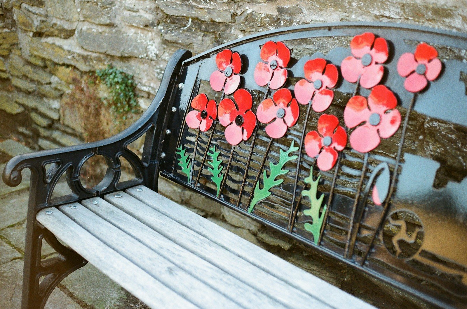 Park bench decorated with red poppy flowers